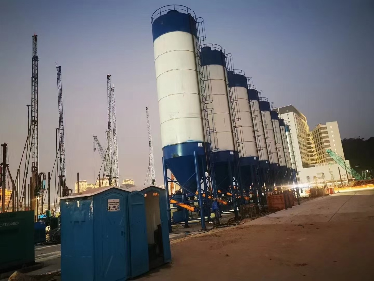Row of bulk cement silos beside jet grouting rigs